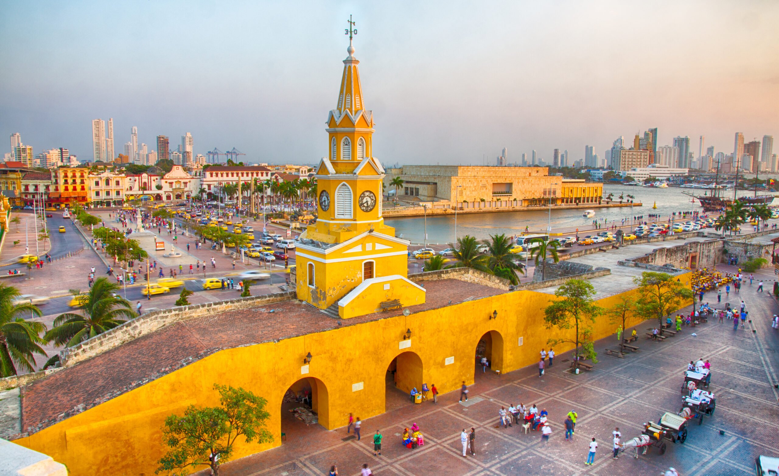 Cartagena, Colombia - February 21st, 2014: Horsedrawn carriages and haukers wait for tourists and restaurant goers in the Plaza San Pedro Claver. The Towers of Bocagrande in the background.